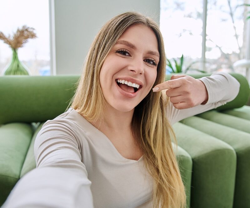 Smiling woman pointing to her healthy teeth, showing the benefits of preventing tooth decay with a Woodbridge, VA dentist