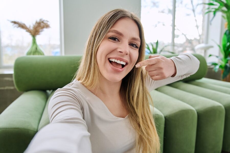 Smiling woman pointing to her healthy teeth, showing the benefits of preventing tooth decay with a Woodbridge, VA dentist