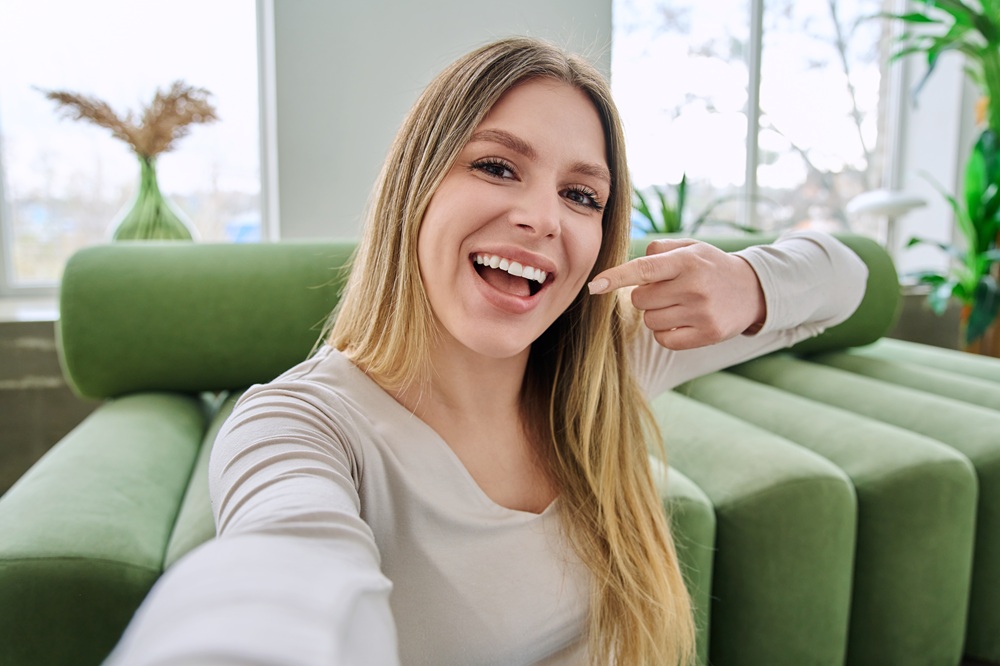 Dental Sealants for a Healthy Smile from a Woodbridge, VA Dentist Smiling woman pointing to her healthy teeth, showing the benefits of preventing tooth decay with a Woodbridge, VA dentist