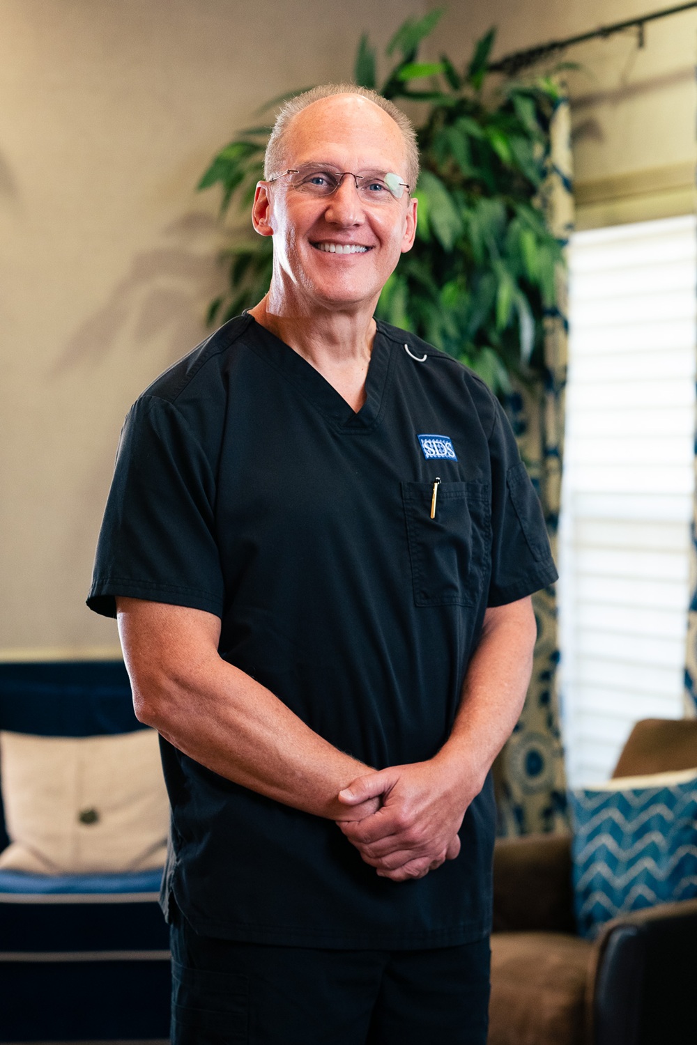 Dr. Steven Strickland, a Woodbridge, VA general and cosmetic dentist, smiling in dark scrubs inside his Northern Virginia dental office 