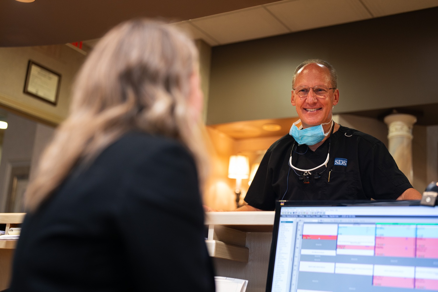 Dr. Strickland smiling and chatting at the front desk of his Woodbridge, VA dental office, serving the Northern Virginia area 
